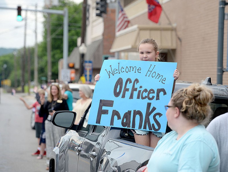 ANDY SHUPE NWA DEMOCRAT-GAZETTE
Brynnley McCulley, 8, holds a sign Wednesday, June 2, as a long line of law enforcement vehicles pass during a parade in downtown Prairie Grove to welcome home Tyler Franks, an officer with the Prairie Grove Police Department who was shot May 4 while responding to a domestic disturbance.