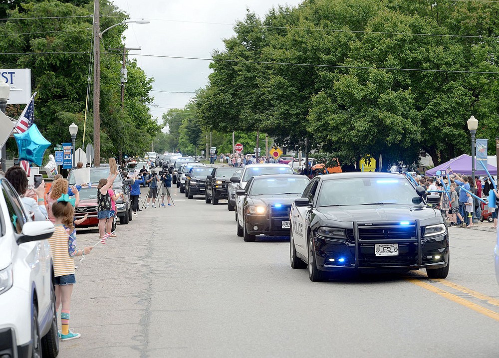 ANDY SHUPE NWA DEMOCRAT-GAZETTE A long line of law enforcement vehicles from across Northwest Arkansas makes its way Wednesday, June 2 through downtown Prairie Grove during a parade to welcome home Tyler Franks, an officer with the Prairie Grove Police Department who was shot May 4 while responding to a domestic disturbance. One observer said the parade included 75 vehicles from 15 agencies.