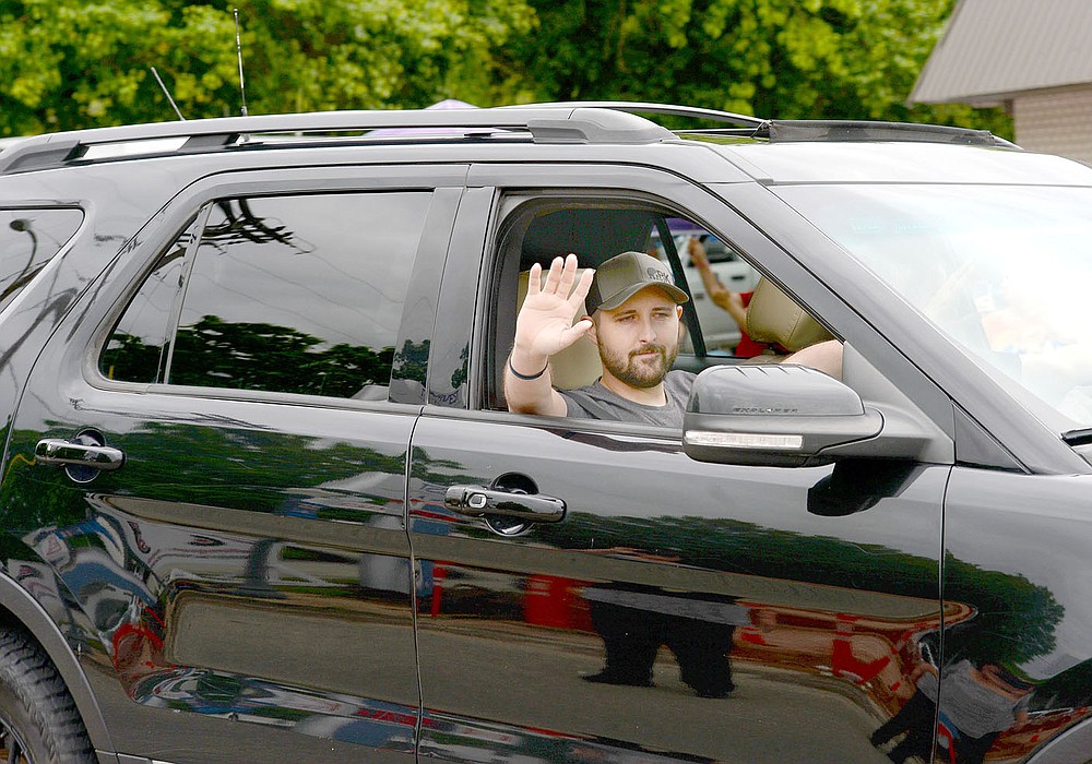 ANDY SHUPE NWA DEMOCRAT-GAZETTE Tyler Franks, an officer with Prairie Grove Police Department, waves at the crowd June 2 during a parade held in his honor and to welcome him home. Franks was shot May 4 while responding to a domestic disturbance.
