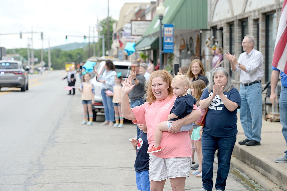 ANDY SHUPE NWA DEMOCRAT-GAZETTE
Angie Huff of Prairie Grove, holding her grandson Baker Redfearn, cheers and waves during a parade in downtown Prairie Grove to welcome home Tyler Franks, an officer with the Prairie Grove Police Department who was shot May 4 while responding to a domestic disturbance. Downtown streets were lined with residents holding signs, flags and other blue paraphernalia for the celebration.