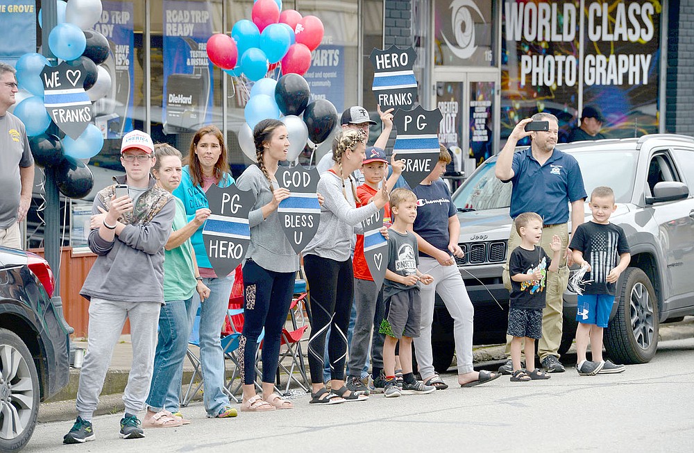 ANDY SHUPE NWA DEMOCRAT-GAZETTE
Residents hold signs Wednesday, June 2, during a parade in downtown Prairie Grove to welcome home Tyler Franks, an officer with the Prairie Grove Police Department who was shot May 4 while responding to a domestic disturbance.