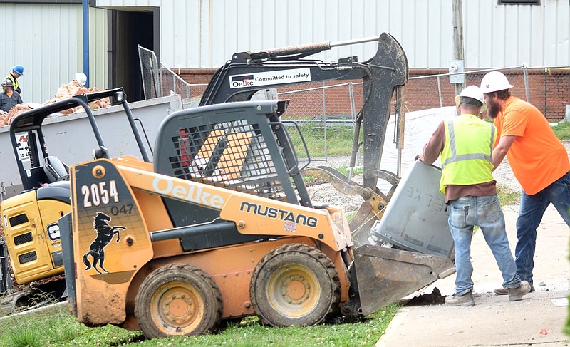 Westside Eagle Observer/MIKE ECKELS
Two workers dump a plastic barrow full of concrete blocks and other debris into a skid loader Thursday morning after tearing down a wall in the old high school Home Economics classroom. The workers are part of the Decatur High School renovation crew working on the north end of the main campus building.