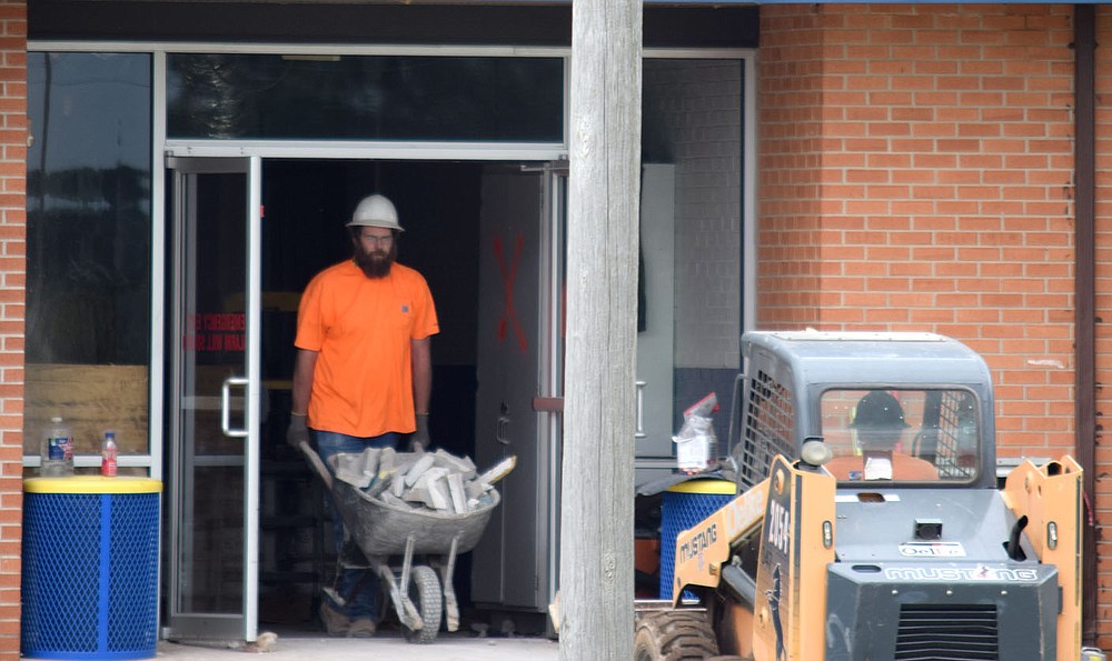 Westside Eagle Observer/MIKE ECKELS
A worker pushes a loaded wheelbarrow full of concrete blocks and other material to a waiting Bobcat loader during the ongoing Decatur High School renovation project in Decatur Thursday morning. Work began on phase two of the project in late April and is expected to be complete sometime around late 2021 or early 2022.