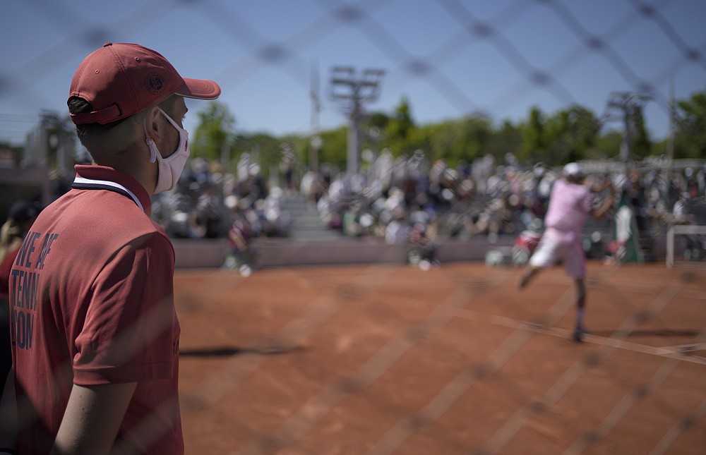 Asistentka súdu s maskou proti hodinkám proti vírusu koróny sa americká Raleigh Opelka vracia do slovenského Andrzeja Martina v pondelok 31. mája 2021, druhý deň prvého kola tenisového turnaja French Open vo francúzskom Roland Crosse.