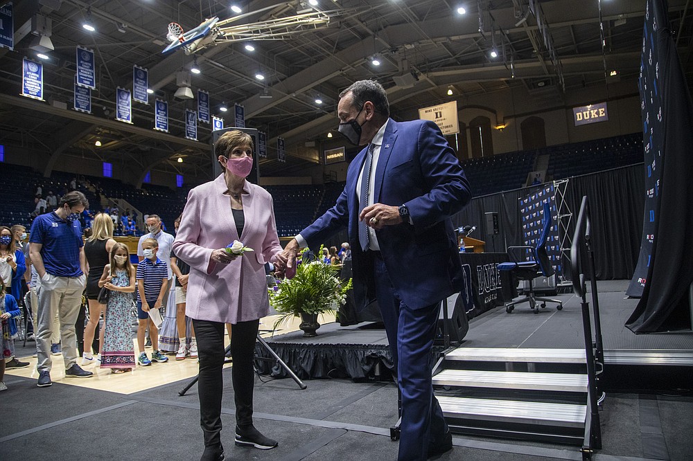 Duke University basketball coach Mike Krzyzewski holds his wife Mickie Krzyzewski's hand as he walks off stage after following an NCAA college basketball news conference  Thursday, June 3, 2021, at Cameron Indoor Stadium in Durham, N.C. Krzyzewski, the winningest coach in the history of Division I men's college basketball announced that next season will be his last with the Blue Devils program he has built into one of college basketball’s bluebloods. The school named former Duke player and associate head coach Jon Scheyer as his successor for the 2022-23 season. (Travis Long/The News & Observer via AP)