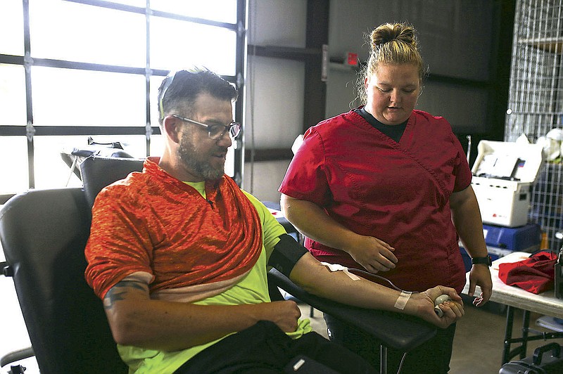 Collection staff Jessica Mitchell (right) draws blood Ryan Patterson of Rogers (left), Friday, June 4, 2021 during a blood drive at Absolute Heat & Air in Lowell. The Red Cross held a blood drive with the goal of collecting 15 units. "We're at a critical need of blood right now," said Red Cross Team Lead Sharm Bloomingdale. "When school is on, you get more donations. Summer months you don't have schools anymore." Check out nwaonline.com/210605Daily/ for today's photo gallery. 
(NWA Democrat-Gazette/Charlie Kaijo)