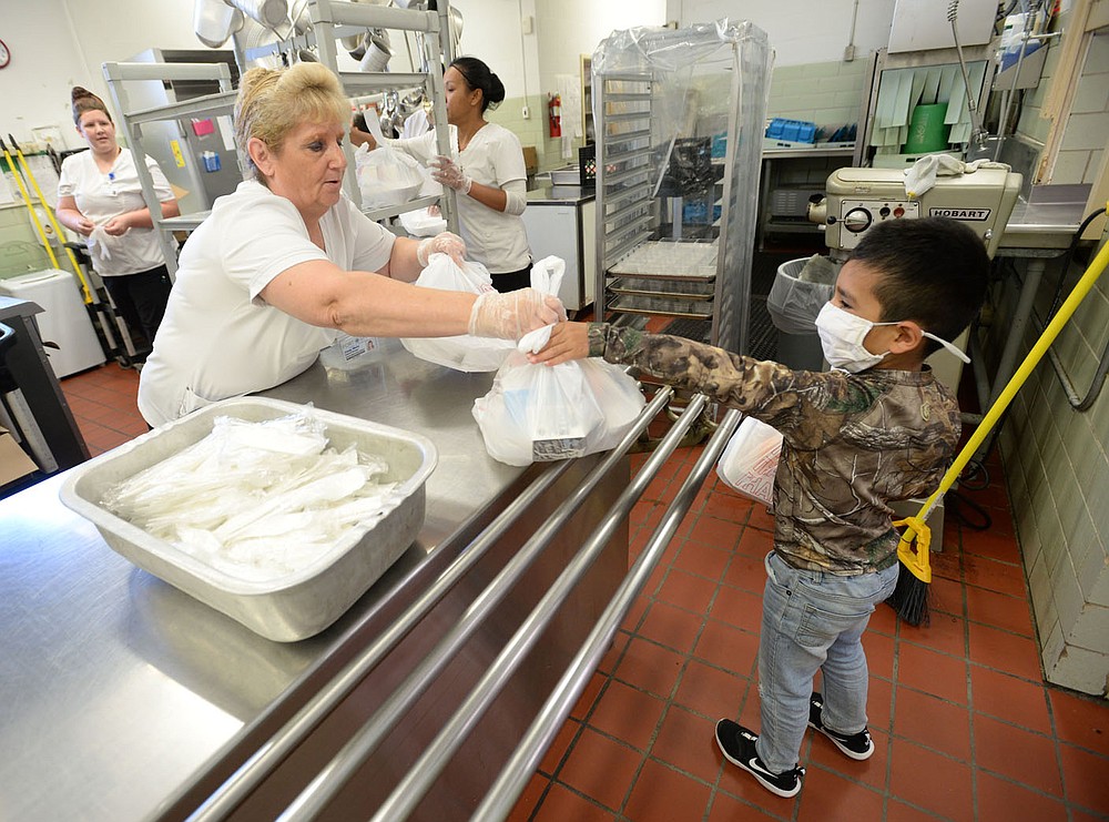 Cindy Wells (left), cafeteria manager at Sutton Elementary School, hands sacked lunches Thursday, June 3, 2021, to Sebastian Uribe, 5, a rising first-grader at the school, while handing out meals to students at the school in Fort Smith. Visit nwaonline.com/210606Daily/ for today's photo gallery.
(NWA Democrat-Gazette/Andy Shupe)