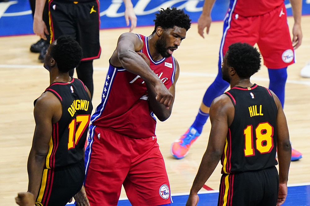 Philadelphia 76ers' Joel Embiid, center, reacts between Atlanta Hawks' Onyeka Okongwu, left, and Solomon Hill after being fouled during the first half of Game 1 of a second-round NBA basketball playoff series, Sunday, June 6, 2021, in Philadelphia. (AP Photo/Matt Slocum)