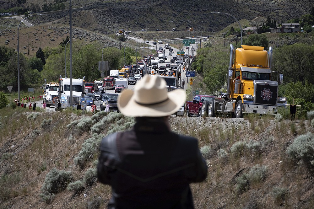 A man watches a convoy of truckers and other vehicles travel on Hwy 5 in support of the Tk'emlups te Secwepemc people after the remains of 215 children were discovered buried near the former Kamloops Indian Residential School, in Kamloops, British Columbia, on Saturday, June 5, 2021. (Darryl Dyck/The Canadian Press via AP)