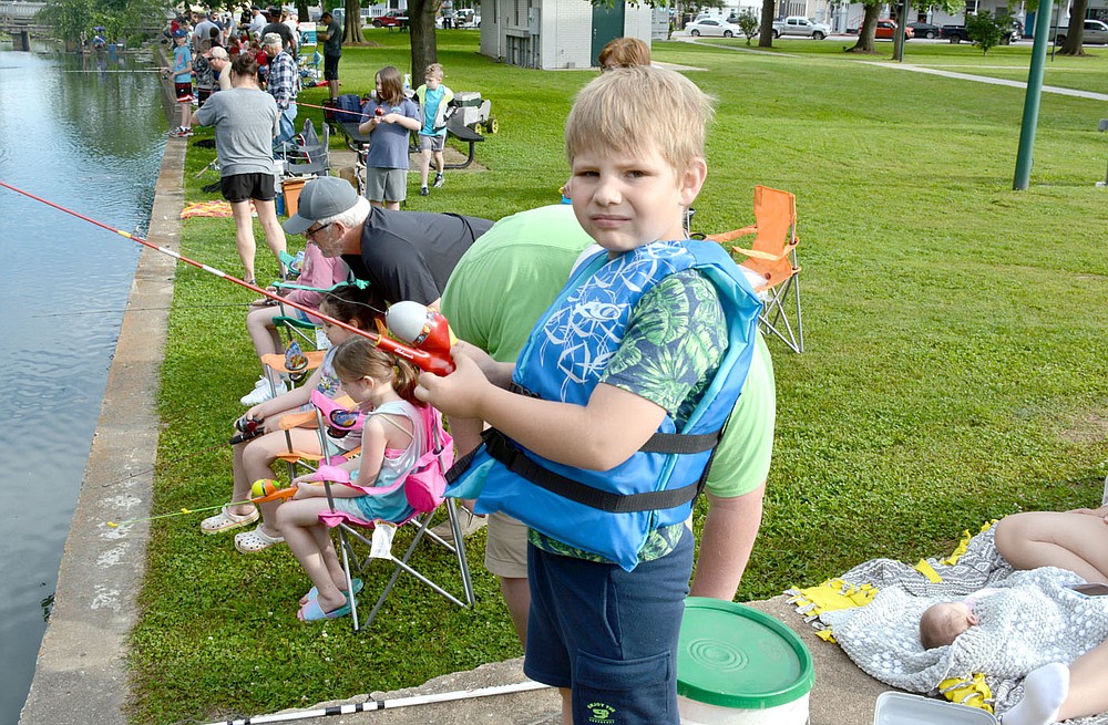 Marc Hayot/Herald-Leader Brandon Melbourne, 8, gets distracted from fishing to pose for a photo at the fishing derby held on Saturday by the Parks and Recreation Department.