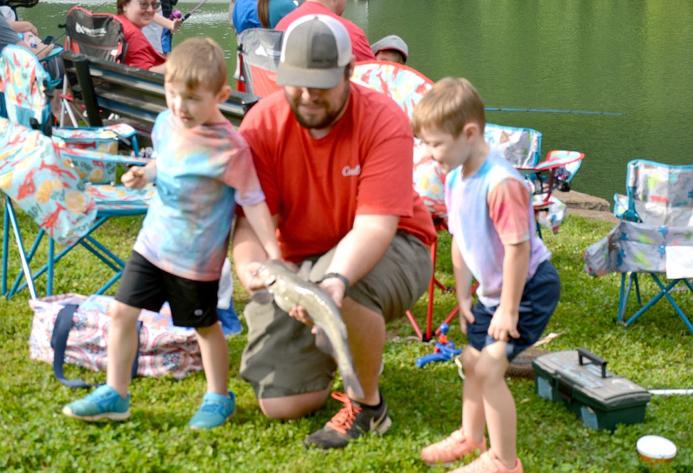Marc Hayot/Herald-Leader Judson Wyatt (right), 4, was one of the big winners of the fishing derby on Saturday. Judson poses with his father Jarred What and his twin brother Jensen Wyatt and their big catch.