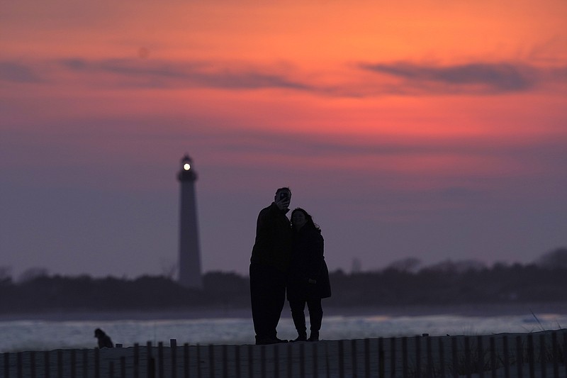 Visitors to Cape May, N.J., watch the sunset behind the Cape May Lighthouse in April. With the ocean on one side and grand Victorian-era houses on the other, Cape May offers an alternate vacation location with expansive views. (AP File Photo/Charles Rex Arbogast)