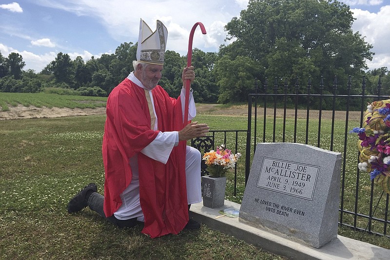 Bill Luckett of Clarksdale, Miss., appearing as a pope, kneels beside the monument for the fictional Billy Joe McAllister made famous by former Greenwood resident Bobbie Gentry’s song “Ode to Billy Joe,” at Tallahatchie Flats near Greenwood, Miss. (Susan Montgomery/The Commonwealth via AP)