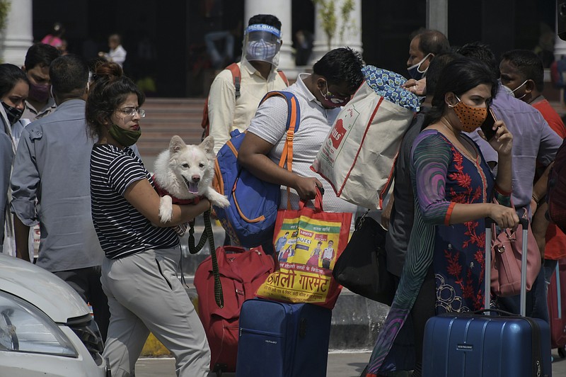 Passengers walk outside the New Delhi railway station in New Delhi, India, Monday, June 7, 2021. Businesses in two of India’s largest cities are reopening as part of a phased easing of lockdown measures in several states now that the number of new coronavirus infections in the country is on a steady decline. (AP Photo/Ishant Chauhan)