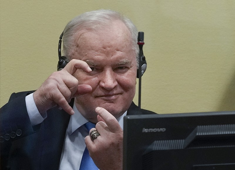 Former Bosnian Serb military chief Ratko Mladic imitates taking pictures as he sits the court room in The Hague, Netherlands, Tuesday, June 8, 2021, where the United Nations court delivers its verdict in the appeal of Mladic against his convictions for genocide and other crimes and his life sentence for masterminding atrocities throughout the Bosnian war. (AP Photo/Peter Dejong, Pool)