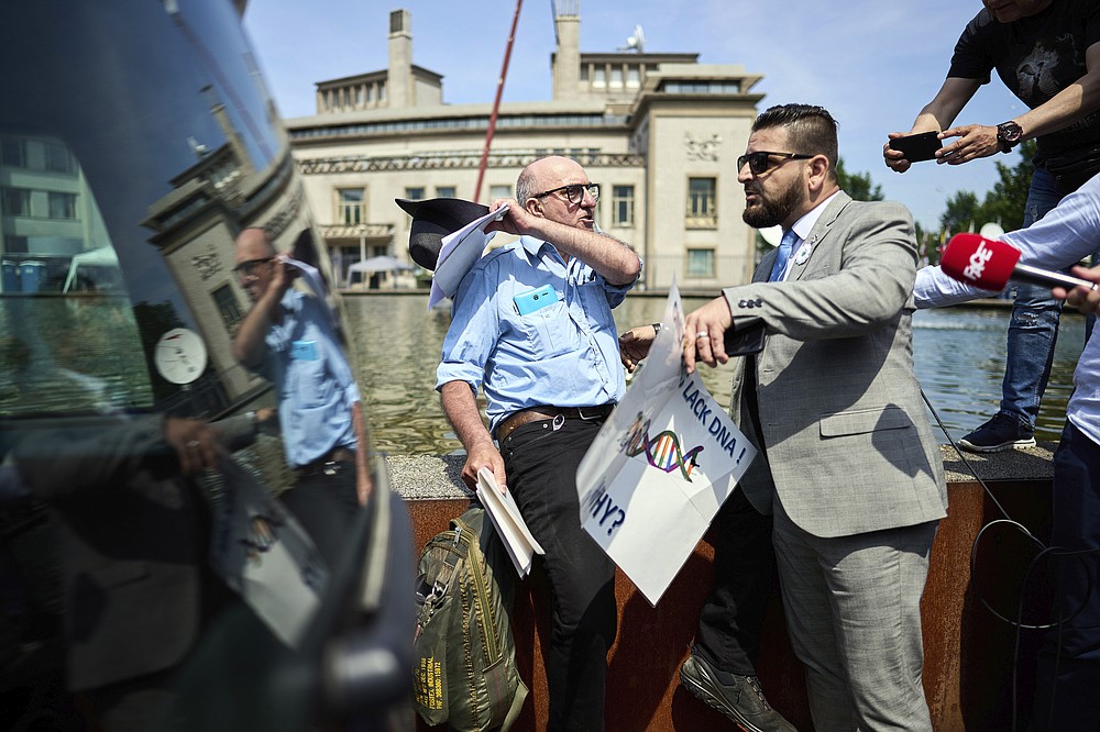 A Ratko Mladic supporter, left, argues with demonstrators outside the International Residual Mechanism for Criminal Tribunals in The Hague, Netherlands, Tuesday, June 8, 2021. The United Nations court delivers its verdict in the appeal by former Bosnian Serb military chief Ratko Mladic against his convictions for genocide and other crimes and his life sentence for masterminding atrocities throughout the Bosnian war. (AP Photo/Phil Nijhuis)