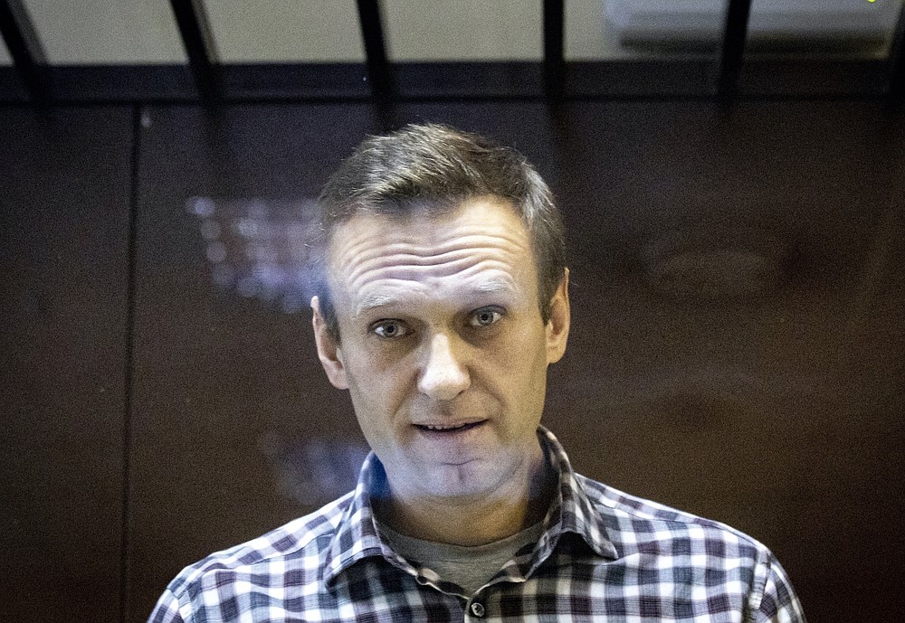 FILE - In this Saturday, Feb. 20, 2021, file photo, Russian opposition leader Alexei Navalny looks at photographers standing in the Babuskinsky District Court in Moscow, Russia. A Moscow court is considering a request by prosecutors to outlaw the organizations founded by Russian opposition leader Alexei Navalny. That's part of authorities’ efforts to muzzle critics ahead of a crucial parliamentary election in September. The Moscow City Court on Wednesday, June 9, 2021 is expected to grant prosecutors’ request to designate Navalny’s Foundation for Fighting Corruption and his sprawling network of regional offices across Russia as extremist organizations. (AP Photo/Alexander Zemlianichenko, File)