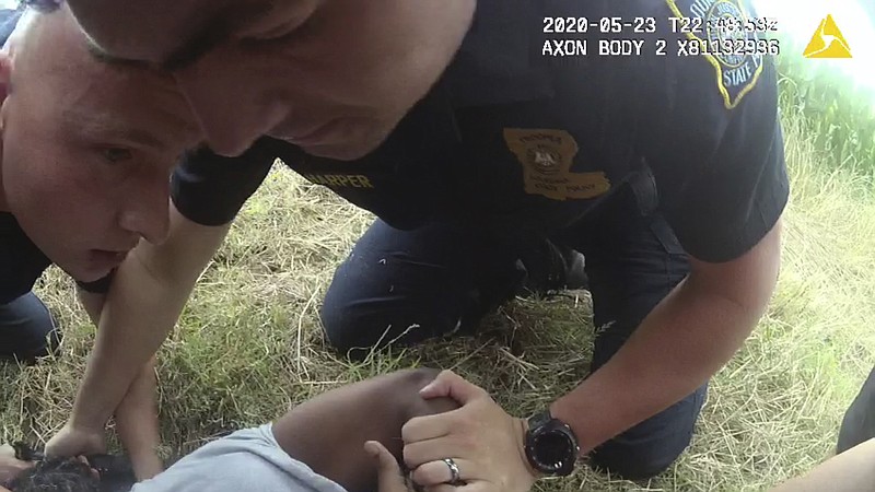 In this Saturday, May 23, 2020 image from Louisiana State Police body camera video, Troopers Jacob Brown, left; George Harper, center, and others restrain motorist Antonio Harris on the ground on the side of a road after a high speed chase in Franklin Parish, La. Troopers exchanged 14 text messages peppered with “lol” and “haha” responses in which they boasted about the beating. “He gonna be sore tomorrow for sure,” Brown texted. “Warms my heart knowing we could educate that young man.” (Larry Shappley/Louisiana State Police via AP)