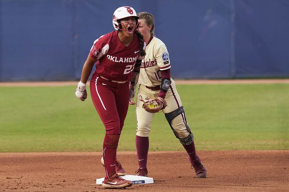 Oklahoma's Tiare Jennings, left, celebrates at second base next to Florida State' Josie Muffley after a double in the first inning of the second game of the NCAA Women's College World Series softball championship series Wednesday, June 9, 2021, in Oklahoma City. (AP Photo/Sue Ogrocki)