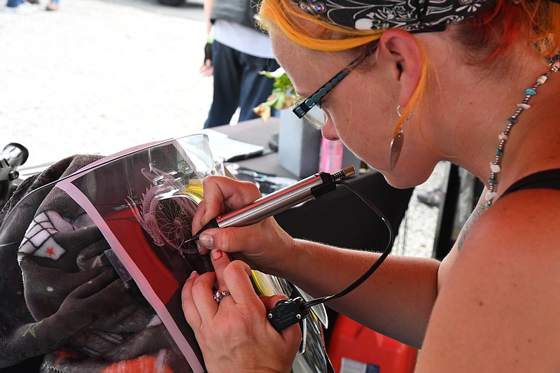 Sara Clark, owner of Tattoo Your Ride in Pearcy, engraves the windshield of a Spyder during the rally. - Photo by Tanner Newton of The Sentinel-Record