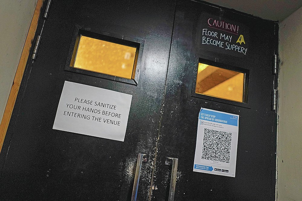 Un letrero adjunto en la puerta de entrada al Moth Club en Hackney pide a los clientes que se desinfecten las manos al entrar en Londres, el domingo 30 de mayo de 2021. El regreso de la música en vivo en la ciudad que produjo bandas desde los Rolling Stones hasta las Spice Girls ha reavivó la creatividad de algunos de los muchos artistas en activo de Londres después de 14 meses de silencio. Jack Milwaukee dice que su inspiración para crear nueva música se redujo a cero durante la pandemia, pero regresó una vez que la hoja de ruta para la reapertura estuvo clara. Los músicos empezaron a tocar de nuevo en Londres el 17 de mayo, pero para multitudes pequeñas y socialmente distanciadas. (Foto AP / Alberto Pezzali)