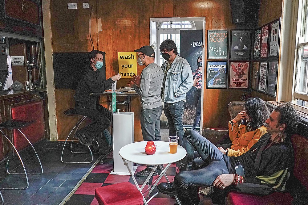 La gente usa máscaras cuando ingresa al Moth Club en Hackney, antes de su show en vivo en el escenario, en Londres, el domingo 30 de mayo de 2021. El regreso de la música en vivo en la ciudad que produjo bandas desde los Rolling Stones hasta las Spice Girls. ha reavivado la creatividad de algunos de los muchos artistas en activo de Londres después de 14 meses de silencio. (Foto AP / Alberto Pezzali)