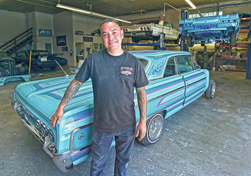 In this Sunday, May 27, 2021, photo, Richard Lopez poses in front of a lowrider he is building for a customer at Auto Color Studio in Reno, Nev. Most recently, his work was center stage at the National Automobile Museum's exhibition, "Low and Slow," in Reno. (Andy Barron/The Reno Gazette-Journal via AP)