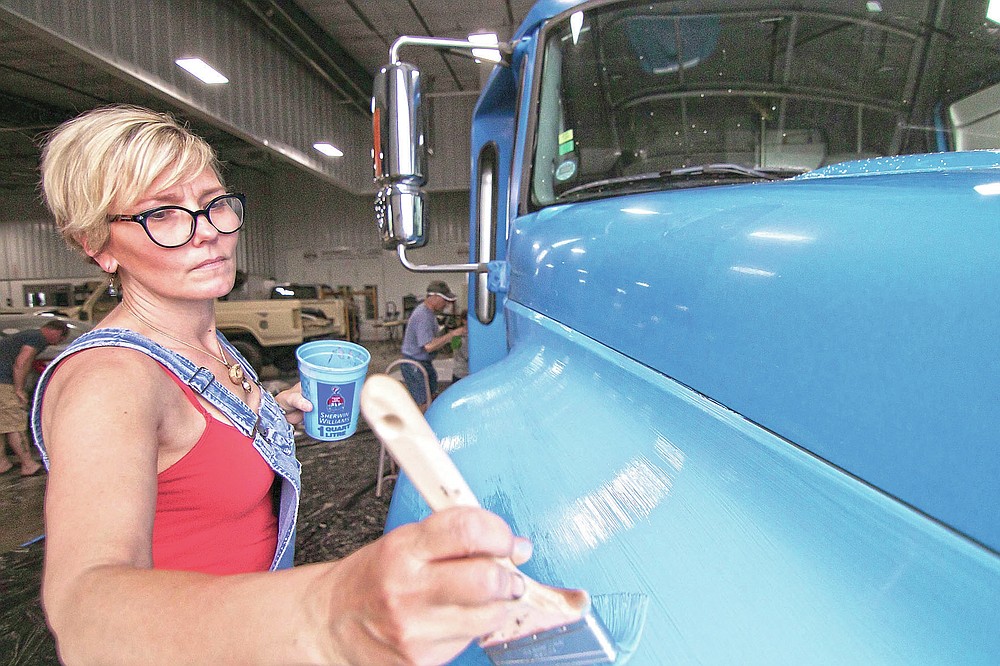 Kelley DeCoste, vice president of a non-profit art initiative called Raw Artwork, works with a team of artists painting a mural on a bus to be used by the Howell Conference and Nature Center for education, in Marion Township, Mich., on Saturday, May 22, 2021. (Gillis Benedict/Livingston County Daily Press & Argus via AP)