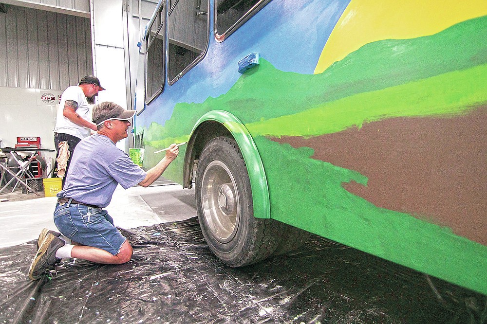 Stacy Karnes, left, and Michael Monroe work on a mural being painted on a bus to be used at the Howell Conference and Nature Center for education, in Marion Township, Mich., on Saturday, May 22, 2021. The effort is part of Raw Artwork's non-profit initiative to provide maker spaces of artwork. (Gillis Benedict/Livingston County Daily Press & Argus via AP)