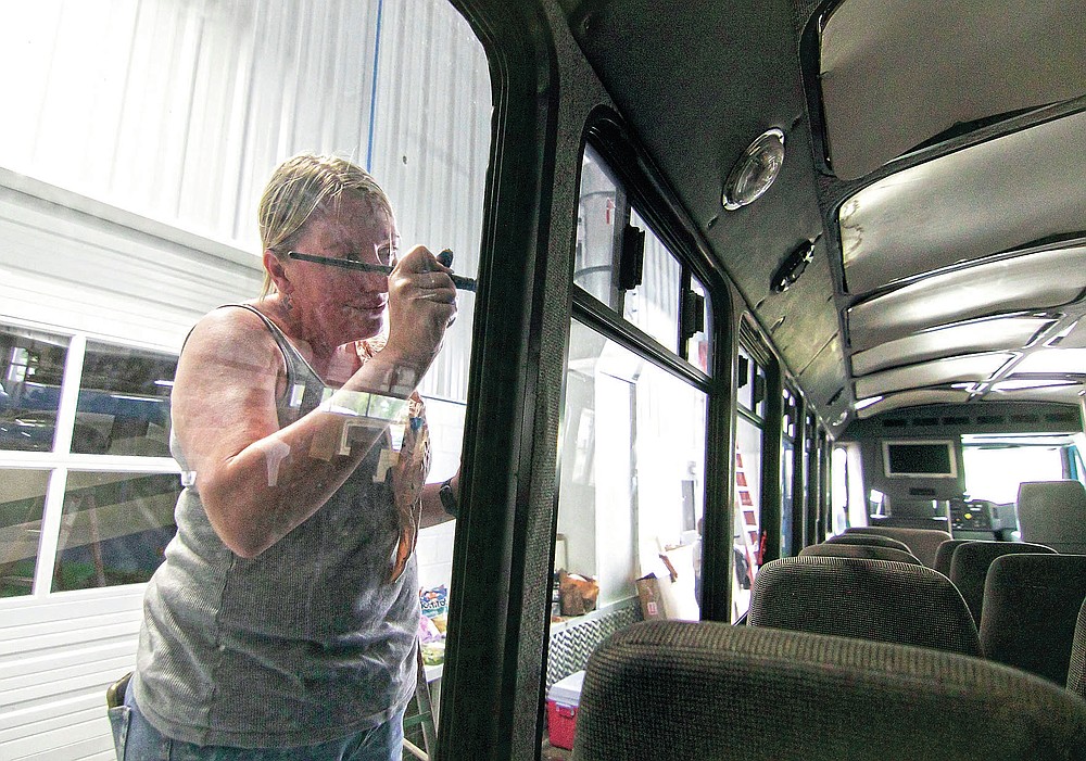 Karrie Martin, one of a number of artists comprising the Raw Artwork initiative, paintw a mural on the exterior of a Howell Conference and Nature Center bus inside Schroeder Auto & RV repair in Marion Township, Mich., on Saturday, May 22, 2021. (Gillis Benedict/Livingston County Daily Press & Argus via AP)