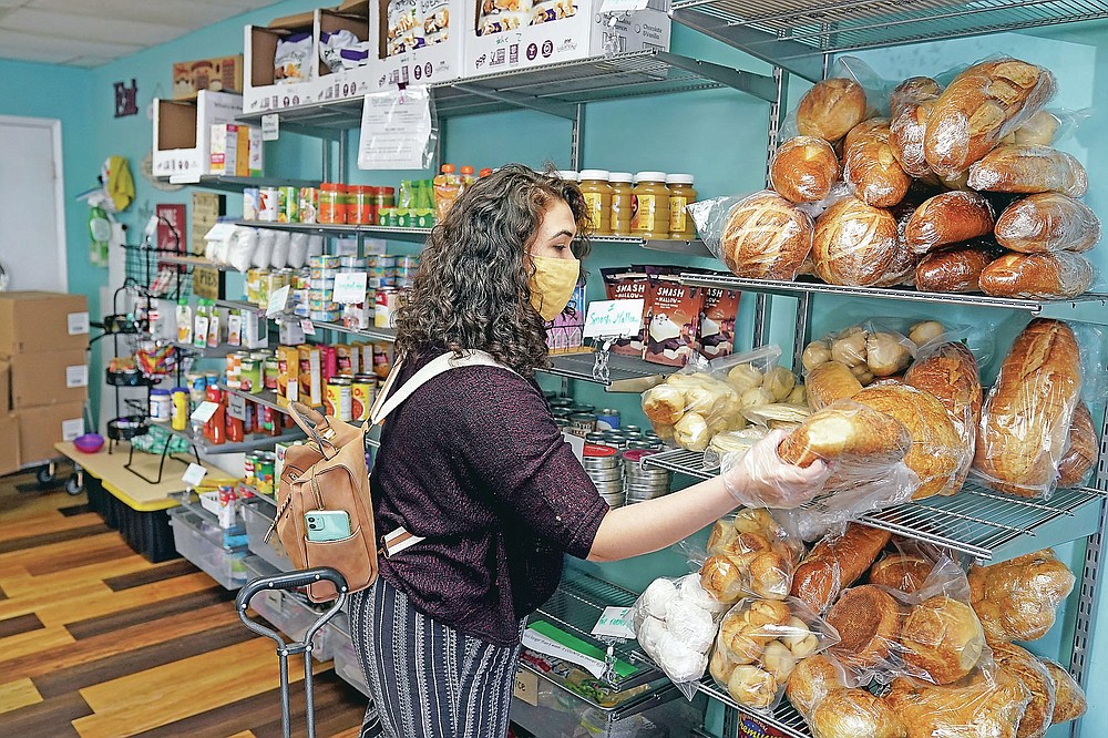 Alex Miller grabs a loaf of bread from a shelf at Porchlight Community Service food pantry Thursday, May 6, 2021, in San Diego. For millions of Americans with food allergies or intolerances, the pandemic has created a particular crisis: Most food banks and government programs offer limited options. (AP Photo/Gregory Bull)