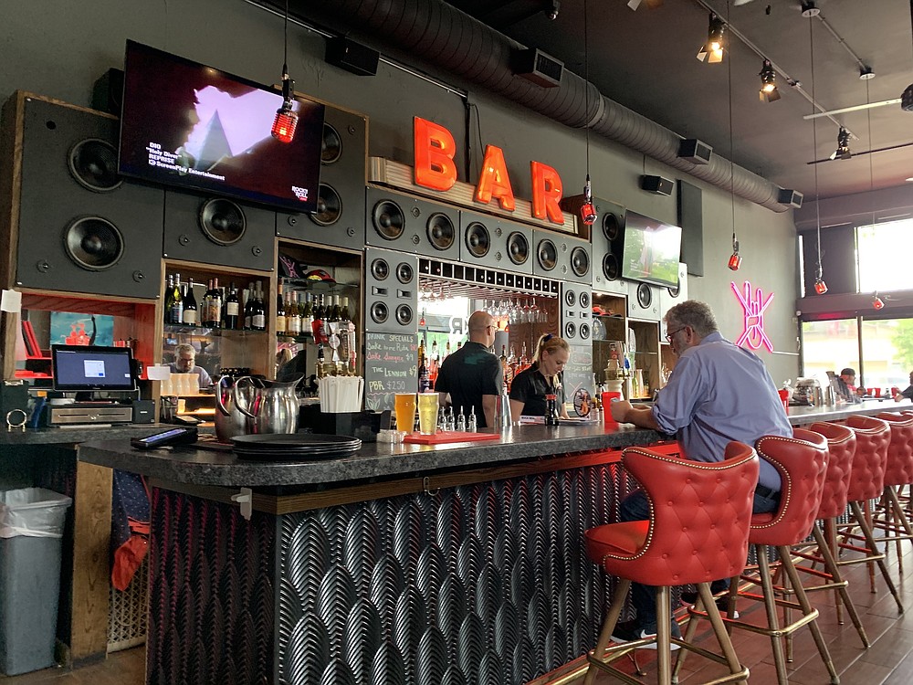 El bar de Rock N Roll Sushi, con una fachada de estilo Art Deco, es el único vestigio que queda del Atlas Bar.  Detrás de la barra, los altavoces indican que la gerencia puede hacer volar a los clientes por las ventanas si reproducen videos musicales que aparecen en las pantallas de televisión.  (Gaceta Demócrata de Arkansas / Eric E. Harrison)