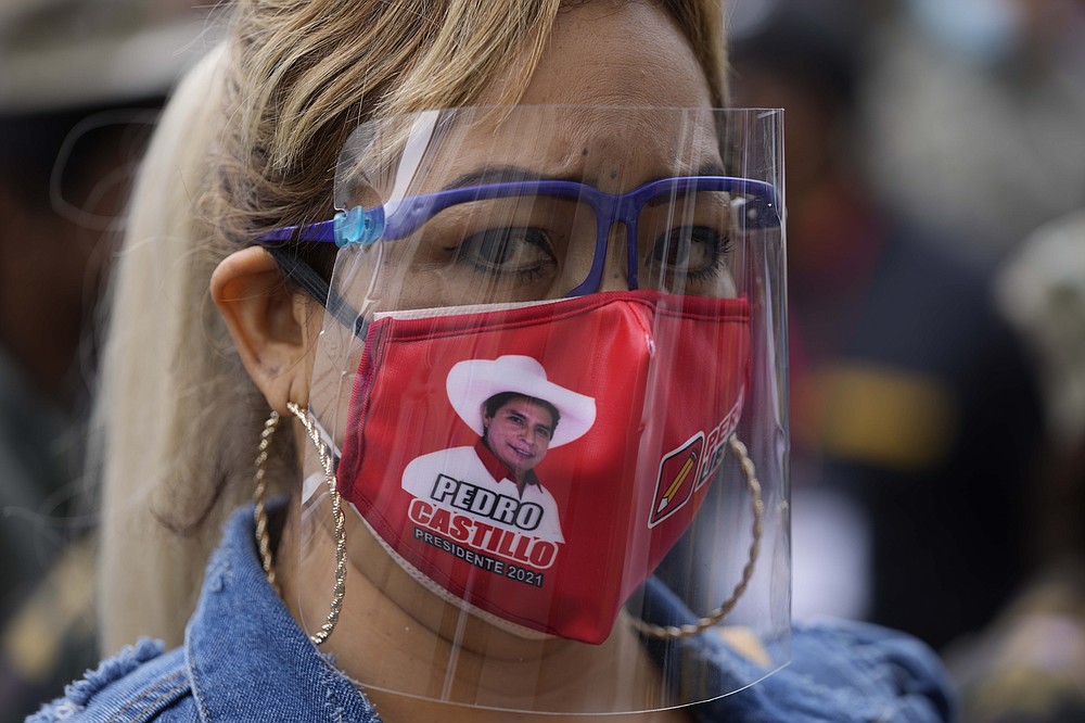 A supporter of presidential candidate Pedro Castillo wears a mask with an image of Castillo, during a march in Lima, Peru, Wednesday, June 9, 2021. Peruvians are still waiting to learn who will become their president next month as votes from Sunday's runoff election continued to be counted and the tiny difference between the two polarizing populist candidates narrowed. (AP Photo/Martin Mejia)