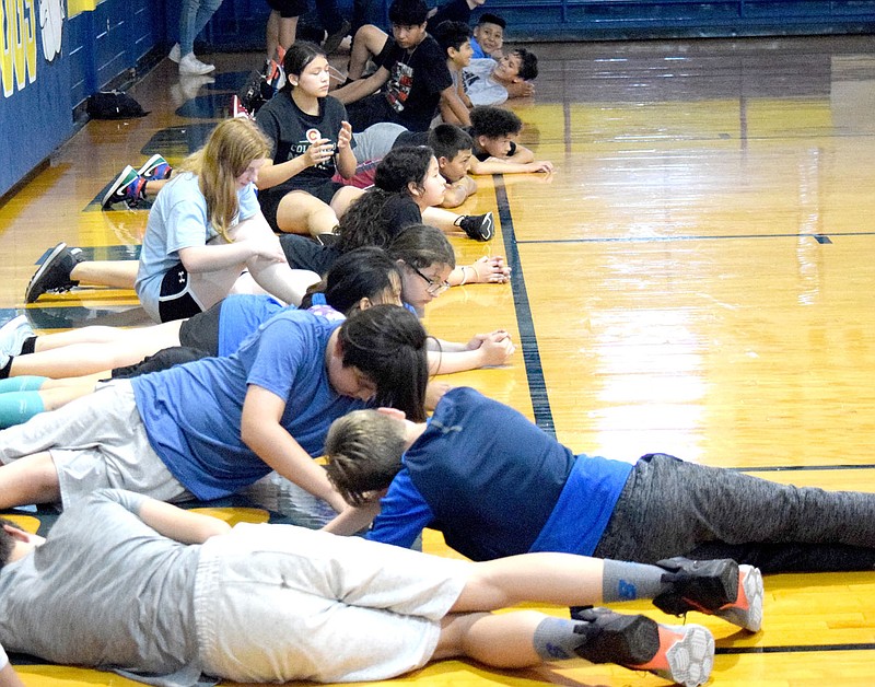 Westside Eagle Observer/MIKE ECKELS

Student athletes use the basketball court floor to stretch out during an exercise session at Peterson Gym in Decatur June 8. The athletes were part of the 2021 Bulldog junior high off season summer camp.