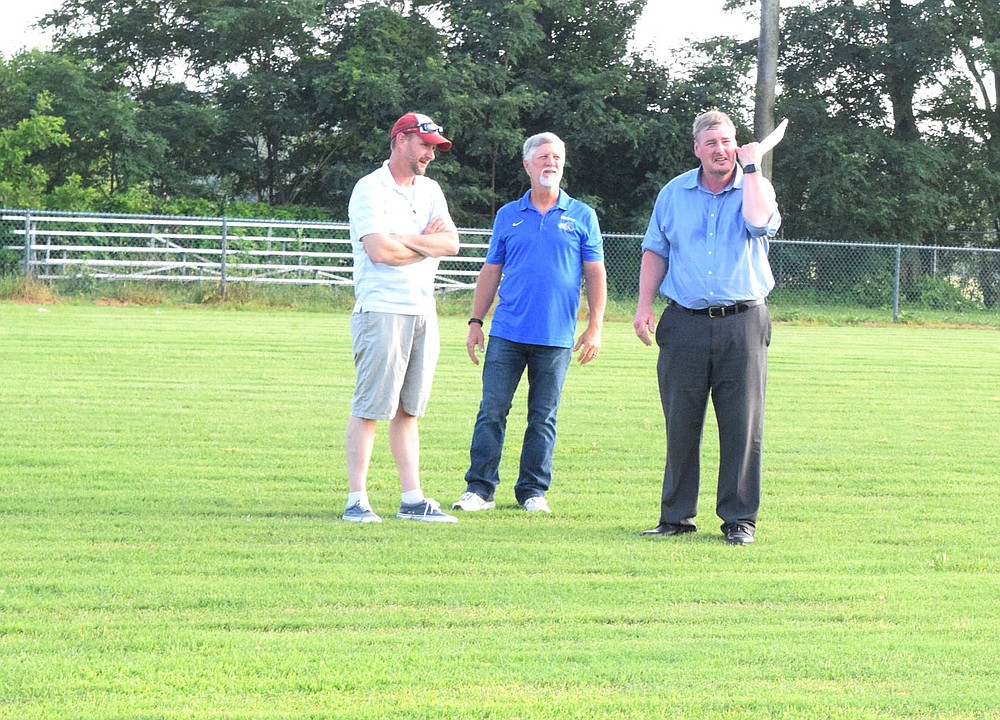 Westside Eagle Observer/MIKE ECKELS
Kevin Smith (left), Ike Owens and Steve Watkins stand at midfield of Bulldog Stadium to get an idea of what the new bleachers may look like during a special school board meeting June 9. The board voted to purchase and move a new set of bleachers from old Cardinal Stadium in Farmington to Decatur, replacing the current aging stands.