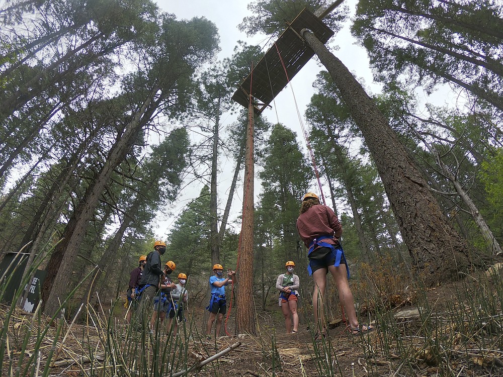 Ahead of campers' arrival in June, counselors at the Glorieta Adventure Camp train in tree rappelling on Friday, May 21, 2021, in Glorieta, N.M. The 3,000-bed camp outside Santa Fe opened up at a third of its normal capacity under pandemic restrictions after being closed last year. Campers and staff will be kept in pods of 10 or less, wear masks outside their sleeping quarters, and eat outdoors to prevent outbreaks. (AP Photo/Cedar Attanasio)