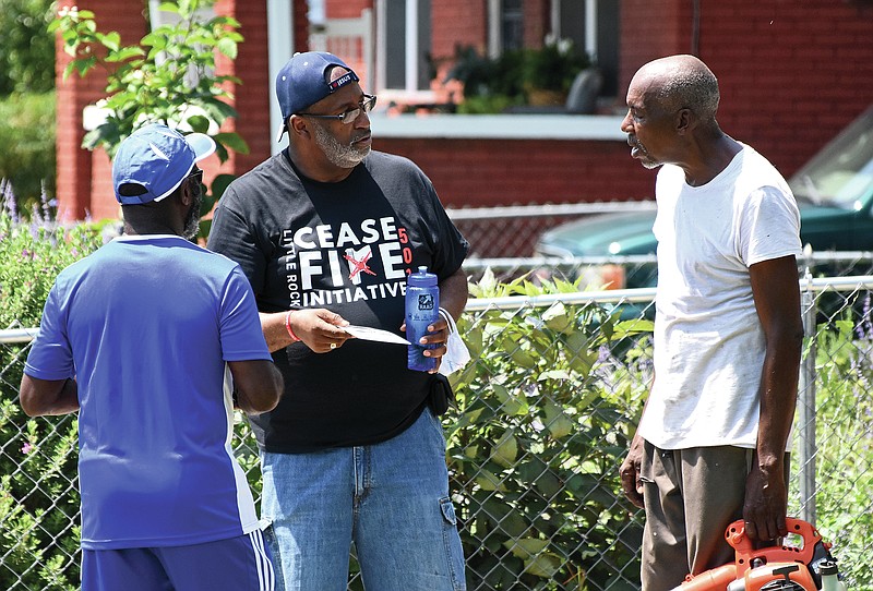 Larry Harris, a member of Phi Beta Sigma fraternity, and Kevin Gupton (center), a staff member of Healing Hearts and Spirits, tell Johnnie Green about “Operation Cease Fire” on Saturday in front of Green’s home in Little Rock. “Operation Cease Fire” is a community outreach program where Little Rock Police Officers meet with residents and encourage them to take the ‘Peacekeep Pledge’ and stop the violence. See more photos at arkansasonline.com/613ceasefire/.
(Arkansas Democrat-Gazette/Staci Vandagriff)