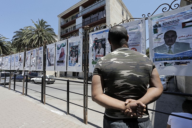 A man looks at electoral posters in Algiers, Wednesday, June 9, 2021. Algerians are preparing for the June 12 elections to elect members of parliament. (AP Photo/Toufik Doudou)