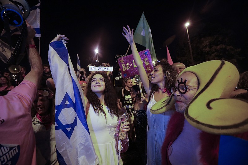 Israelis celebrate the swearing in of the new government in Jerusalem, Sunday, June 13, 2021. Israel's parliament has voted in favor of a new coalition government, formally ending Prime Minister Benjamin Netanyahu's historic 12-year rule. Naftali Bennett, a former ally of Netanyahu, became the new prime minister. (AP Photo/Sebastian Scheiner)