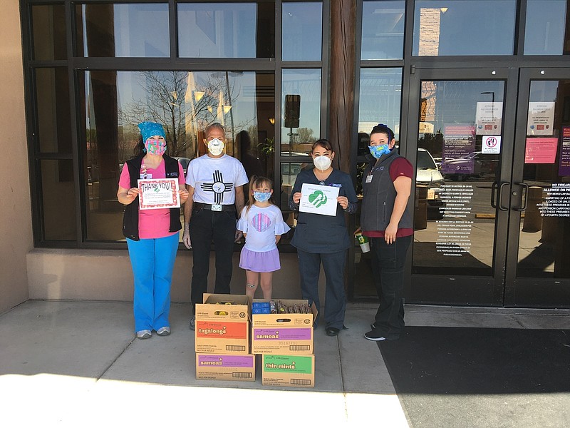 This April 30, 2020 image provided by Girl Scouts of New Mexico Trails shows health care workers with Christus St. Vincent Health System in Santa Fe, New Mexico, accepting a donation of cookies as part of the Hometown Heroes program. As the coronavirus pandemic wore into the spring selling season, many Girl Scout troops nixed their traditional cookie booths for safety reasons. That resulted in millions of boxes of unsold cookies. (Girl Scouts of New Mexico Trails via AP)