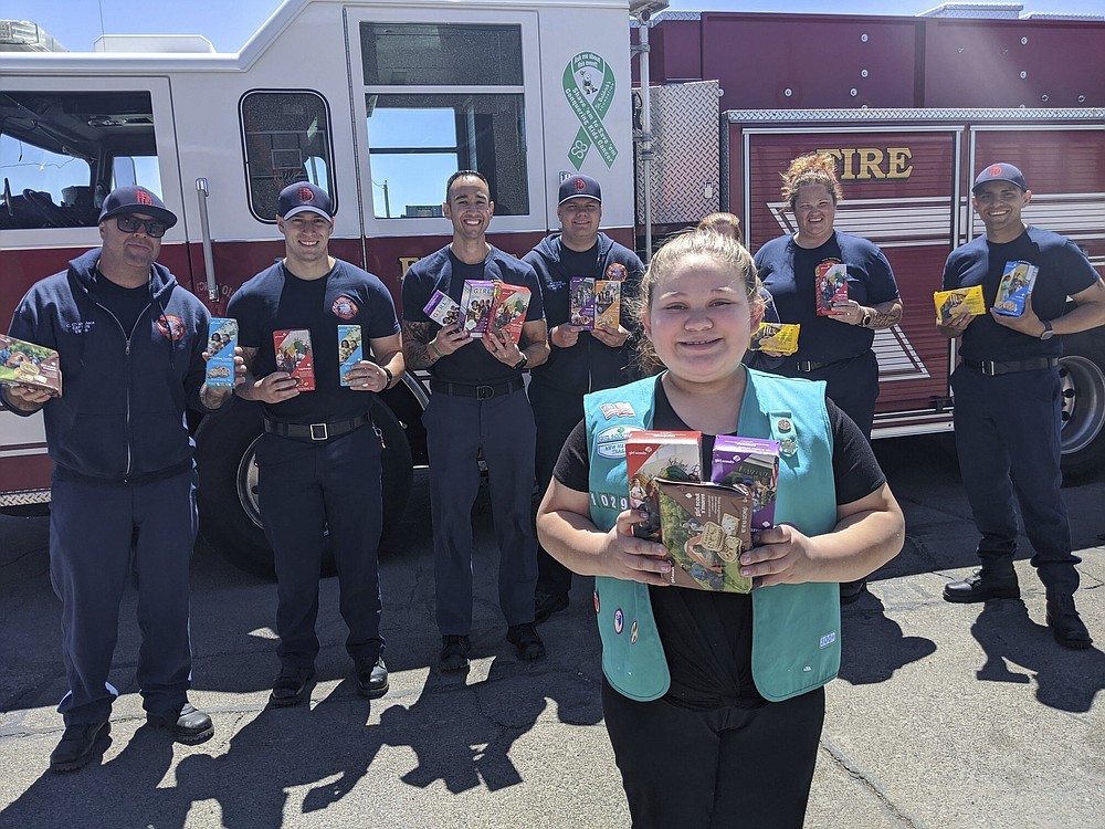 This undated photo provided by Girl Scouts of New Mexico Trails shows a scout donating cookies to firefighters in Rio Rancho, New Mexico, as part of the Hometown Heroes program. As the coronavirus pandemic wore into the spring selling season, many Girl Scout troops nixed their traditional cookie booths for safety reasons. That resulted in millions of boxes of unsold cookies. (Girl Scouts of New Mexico Trails via AP)