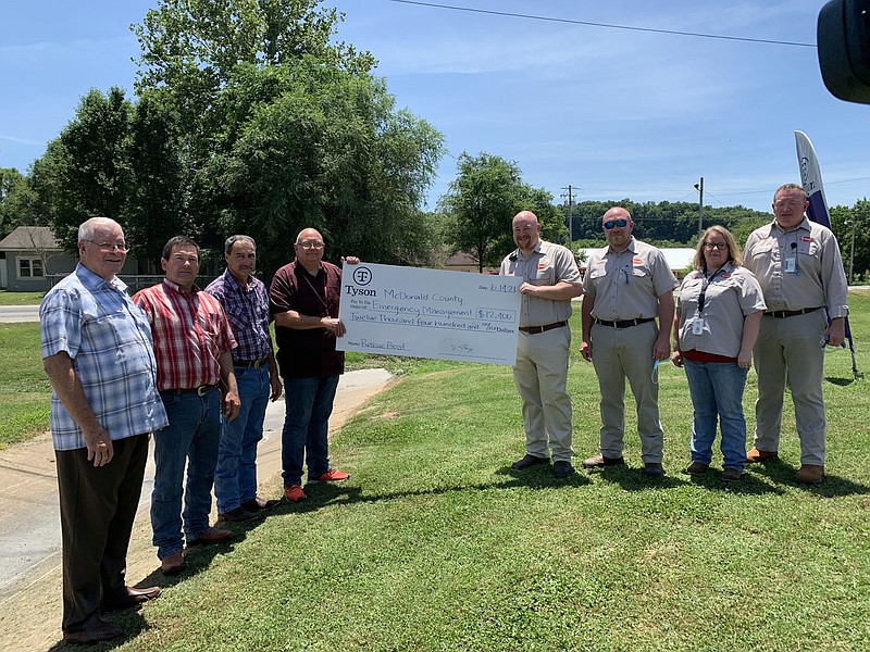 PHOTOS BY ALEXUS UNDERWOOD/SPECIAL TO MCDONALD COUNTY PRESS Tyson and McDonald County leadership were presented with a $12,400 check donated by Tyson. Tyson’s complex manager, Nathan McKay (standing on the right with sunglasses), knew McDonald County Emergency Management employees (left to right), Bill Lant, Rick Lett, Jamey Cope and Gregg Sweeten, lacked a reliable boat before the donation.