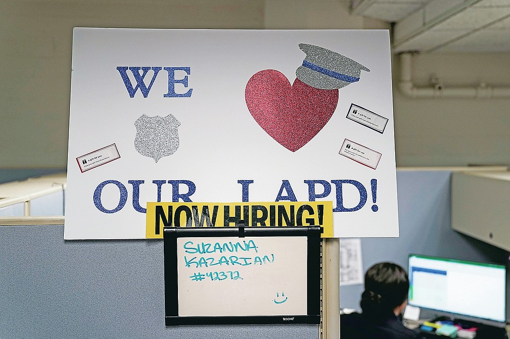 In this Sept. 9, 2020, photo a "Now Hiring" sign is placed on a cubicle wall in the office of the Los Angeles Police recruitment and employment division in Los Angeles. (AP Photo/Jae C. Hong)