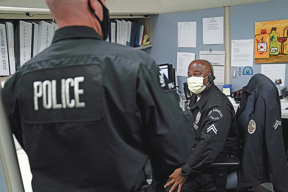 In this Sept. 9, 2020, photo Los Angeles Police recruitment officers, Dion Gourdine, right, and Christopher Hoffman, chat in the office in Los Angeles. (AP Photo/Jae C. Hong)