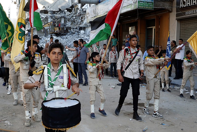A Scout marching band pass a building destroyed by an Israeli airstrike, during a protest against a march by Jewish ultranationalists through east Jerusalem, along the streets of Gaza City, Tuesday, June 15, 2021. (AP Photo/Adel Hana)