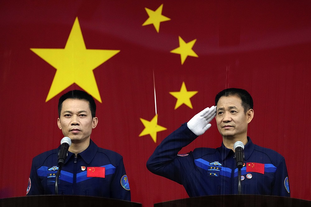 Chinese astronauts Nie Haisheng, right, salutes as he and fellow astronaut Tang Hongbo attend a press conference at the Jiuquan Satellite Launch Center ahead of the Shenzhou-12 launch from Jiuquan in northwestern China, Wednesday, June 16, 2021. China plans on Thursday to launch three astronauts onboard the Shenzhou-12 spaceship, who will be the first crew members to live on China's new orbiting space station Tianhe, or Heavenly Harmony from the Jiuquan Satellite Launch Center in northwest China. (AP Photo/Ng Han Guan)