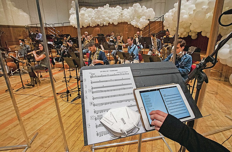 Giuseppe Verdi jazz orchestra musicians and singers play their instruments behind a transparent panel to curb the spread of COVID-19 during a rehearsal at the Giuseppe Verdi Music Conservatory, in Milan, Italy, Friday, May 7, 2021. Whatever the instrument, flute, violin or drums, students at Italy's oldest and largest music conservatory have been playing behind plexiglass screens during much of the pandemic as the Conservatory found ways to preserve instruction throughout Italy’s many rolling lockdowns. (AP Photo/Antonio Calanni)