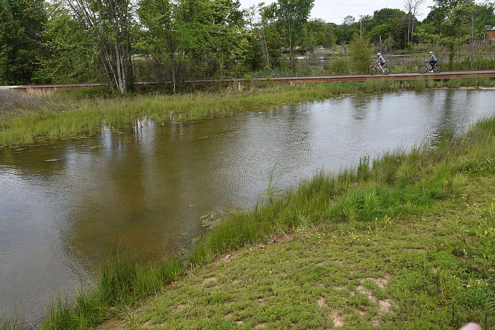 Bikers roll across the wetland near the Lake Bentonville spillway at Osage Park.
(NWA Democrat-Gazette/Flip Putthoff)