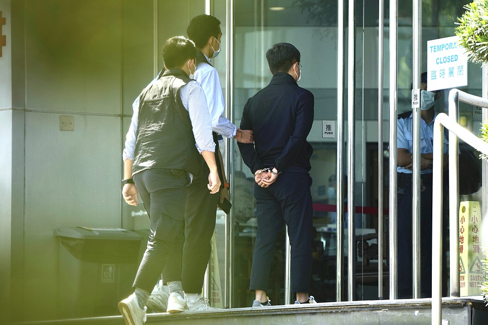 Police officers escort Ryan Law, Apple Daily's chief editor, at the Apple Daily headquarters in Hong Kong, Thursday, June 17, 2021. Hong Kong police on Thursday morning arrested the chief editor and four other senior executives of Apple Daily under the national security law on suspicion of collusion with a foreign country to endanger national security, according to local media reports. (AP Photo/Kin Cheung)