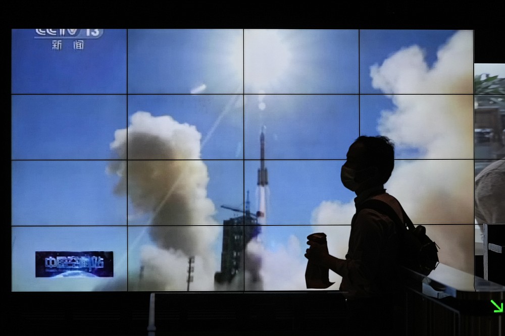 A man is silhouetted as she walks by a TV screen showing CCTV live telecast of the Long March-2F Y12 rocket carrying a crew of Chinese astronauts in a Shenzhou-12 spaceship lifts off at the Jiuquan Satellite Launch Center, at a shopping mall in Beijing, Thursday, June 17, 2021. China launched the first three crew members on a mission to its new space station Thursday in its first crewed mission in five years. (AP Photo/Andy Wong)